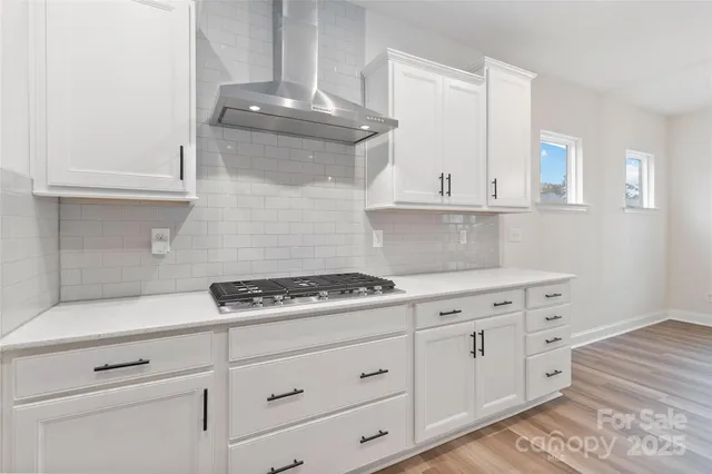 a kitchen with white cabinets and a stove with wooden floor
