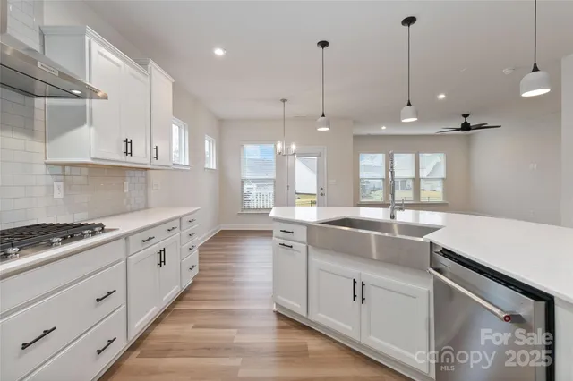 a large white kitchen with kitchen island a stove a sink a center island and wooden floor