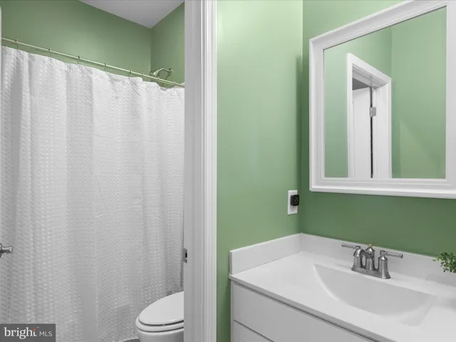 a large kitchen with stainless steel appliances kitchen island granite countertop a refrigerator a sink dishwasher a stove and white cabinets with wooden floor