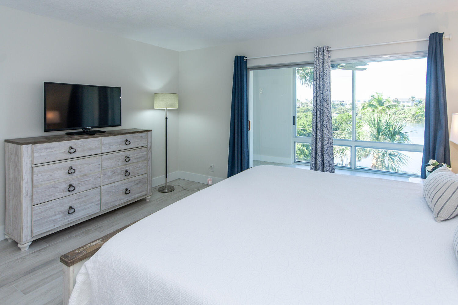 120 Celestial Way, Unit 302 Juno Beach, FL 33408 - Photo 20 of 55 a bedroom with a large bed and a flat tv screen on dresser