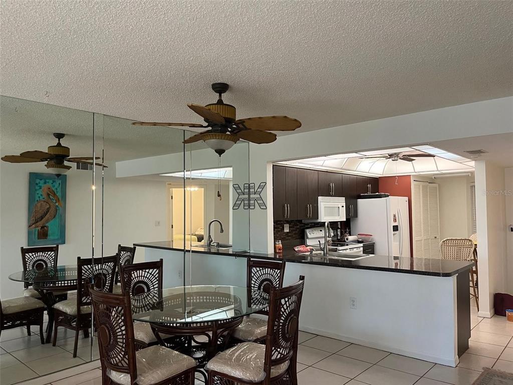 23465 Harbor View Road, Unit 1006 Punta Gorda, FL 33980 - Photo 8 of 41 a kitchen with a dining table chairs and white cabinets