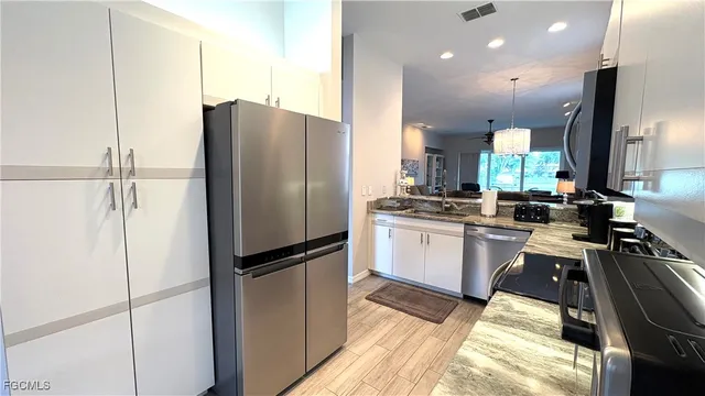 a kitchen with granite countertop a refrigerator a sink a counter top space and cabinets