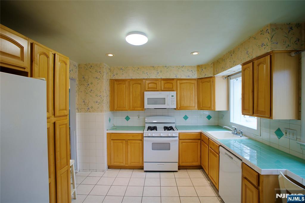 524 Studio Road, Unit 1 Ridgefield, NJ 07657 - Photo 18 of 44 a kitchen with a sink a stove top oven a refrigerator a counter top space and cabinets