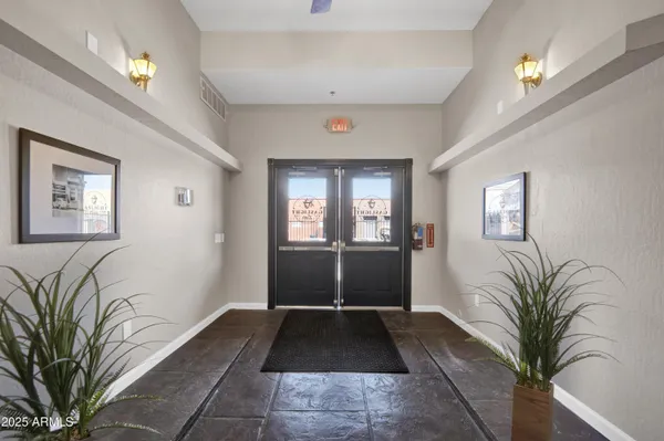 a living room with a large window and potted plants