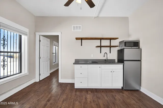 a kitchen with stainless steel appliances granite countertop a refrigerator a sink and white cabinets