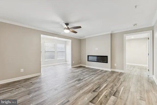 a view of empty room with wooden floor and fan