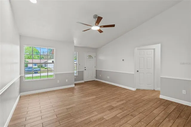 an empty room with wooden floor and windows