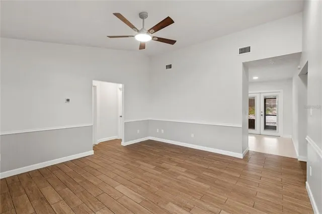 an empty room with wooden floor and windows