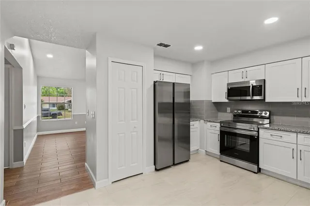 a kitchen with stainless steel appliances granite countertop a refrigerator and a stove top oven