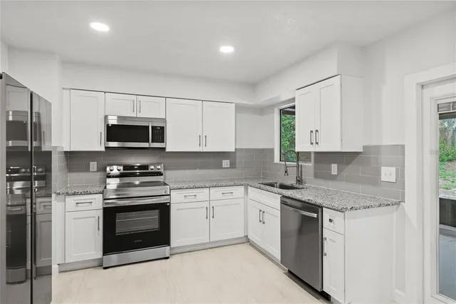 a kitchen with granite countertop white cabinets stainless steel appliances and a sink