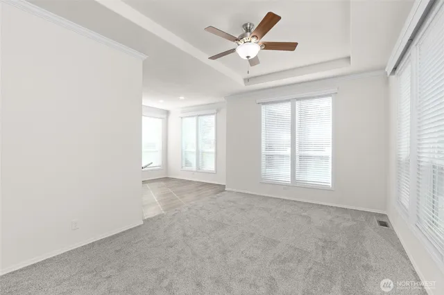 an empty room with windows and ceiling fan