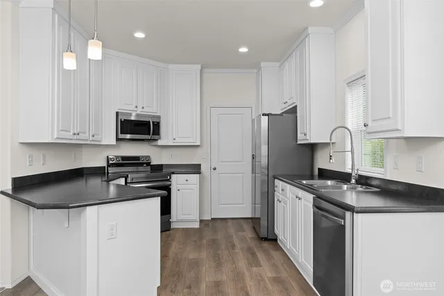 a kitchen with stainless steel appliances granite countertop a stove a refrigerator a sink a microwave and cabinets