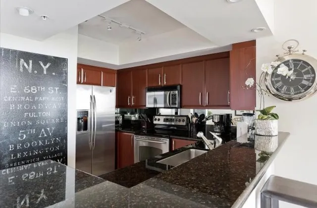 a kitchen with stainless steel appliances granite countertop a refrigerator a stove top oven a sink and dishwasher