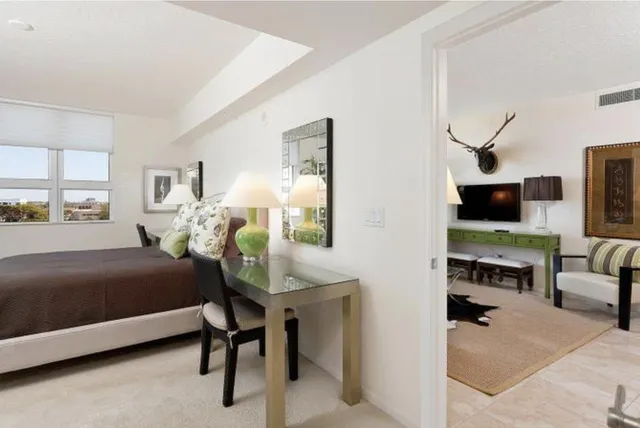 a bedroom with a bed table chair and a window