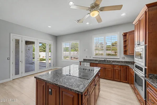 a kitchen with granite countertop center island a sink dishwasher a stove and a refrigerator with wooden floor