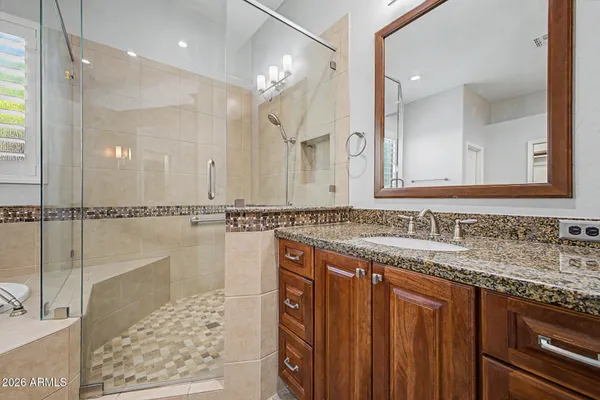 a bathroom with a granite countertop sink a mirror and a shower