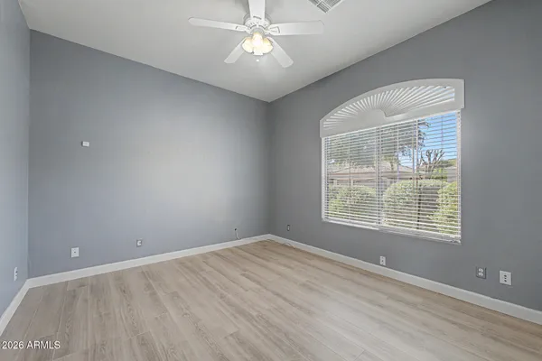 an empty room with a window and a chandelier fan