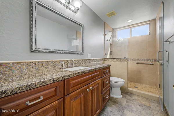 a bathroom with a granite countertop sink a toilet and a mirror