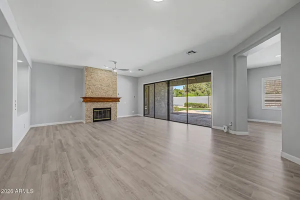 an empty room with wooden floor fireplace and windows