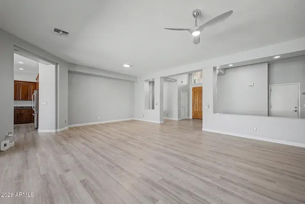 a view of an empty room with wooden floor ceiling fan