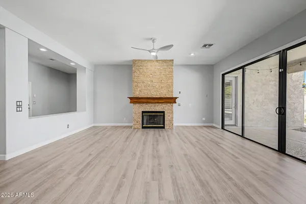 an empty room with wooden floor fireplace and windows