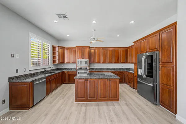 a kitchen with stainless steel appliances granite countertop a stove a sink dishwasher a refrigerator and a oven with wooden floor