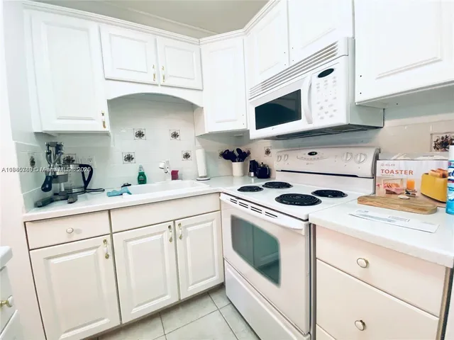 a kitchen with white cabinets and white appliances