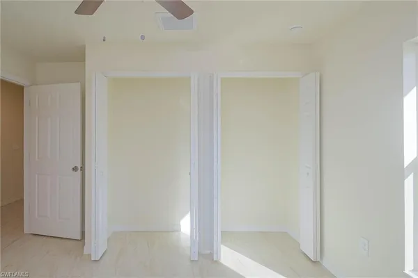 an empty room with a window and a ceiling fan