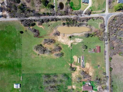 an aerial view of a residential houses with outdoor space and trees all around