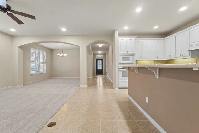 an empty room with a window and chandelier fan