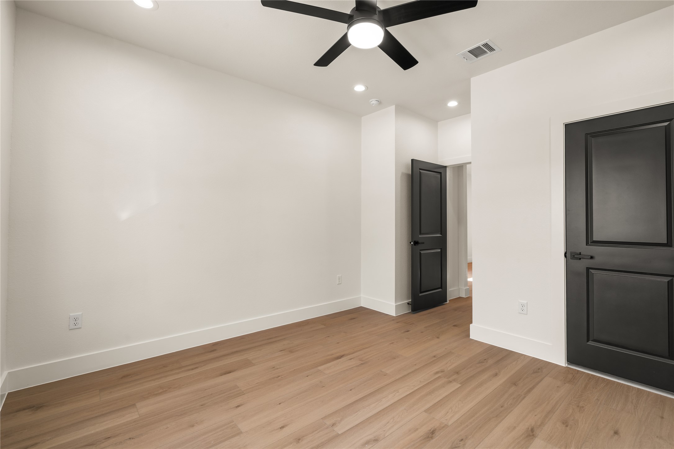5321 Rue Street Houston, TX 77033 - Photo 13 of 23 Versatile second bedroom — crisp modern contrast with matte black doors, ceiling fan light kit, and generous wall space.