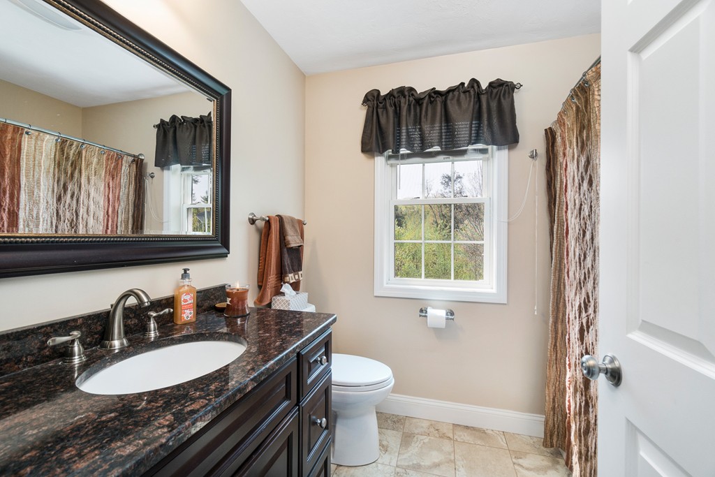27 Michael Drive Rutland, MA 01543 - Photo 18 of 30 a bathroom with a granite countertop sink a mirror a window and a toilet
