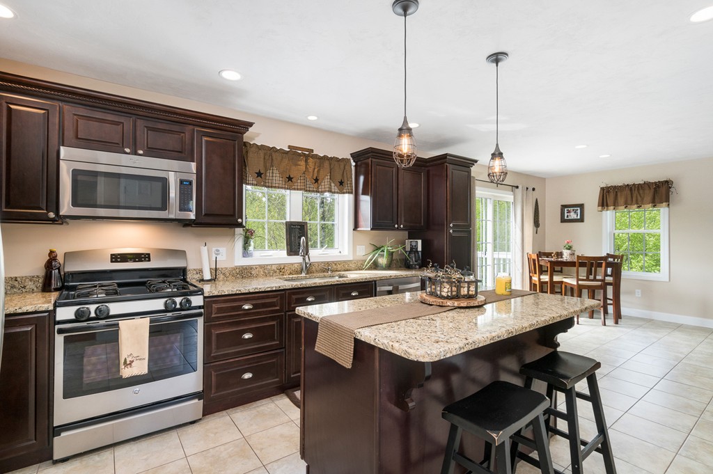 27 Michael Drive Rutland, MA 01543 - Photo 6 of 30 a kitchen with stainless steel appliances granite countertop a stove a sink a microwave a dining table and chairs