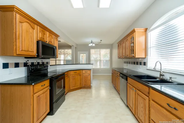 a large kitchen with stainless steel appliances granite countertop a stove a sink and a microwave