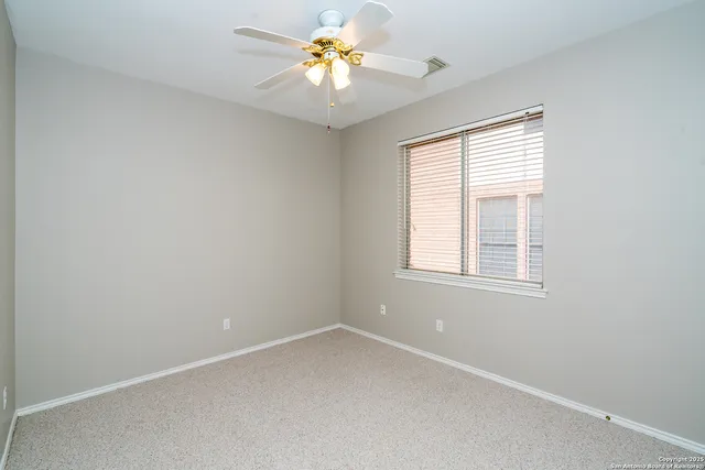 an empty room with a window and a fan