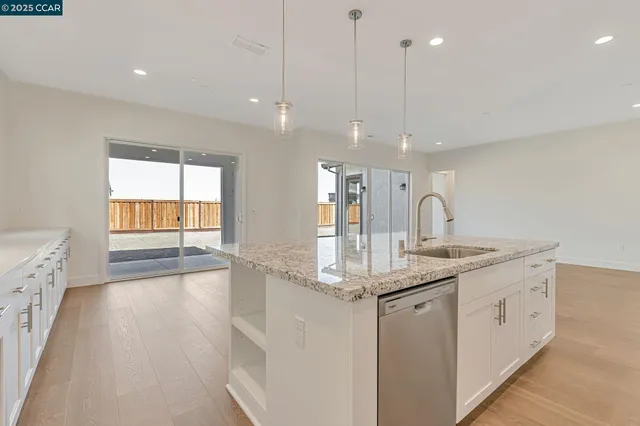 a kitchen with stainless steel appliances granite countertop a sink a oven a dining table and chairs