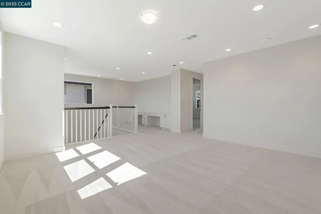 a view of an empty room with wooden floor and a bathroom