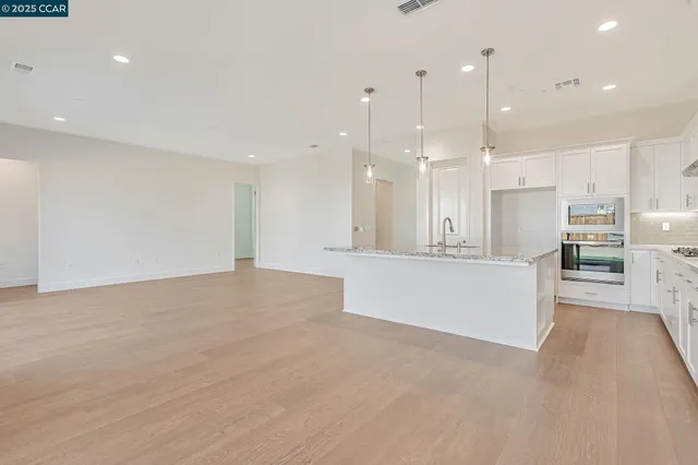 a view of kitchen with kitchen island white cabinets and stainless steel appliances
