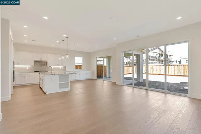 a view of an empty room and kitchen with a large window