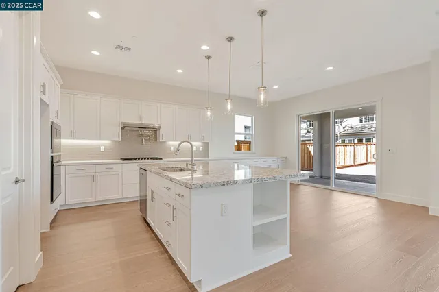 a kitchen with kitchen island granite countertop a sink counter top space stainless steel appliances and windows