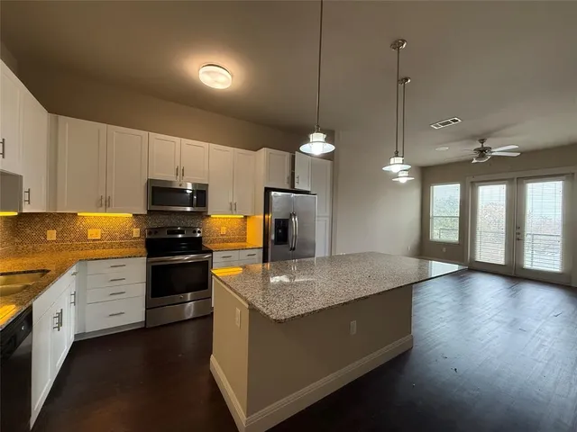 a kitchen with stainless steel appliances granite countertop a sink a stove and a wooden floors
