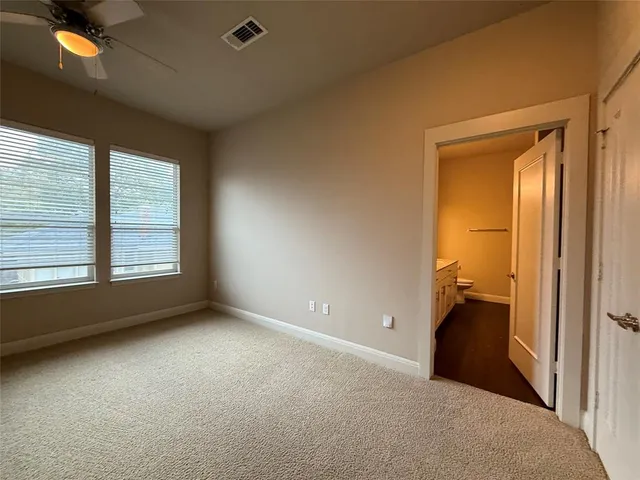 an empty room with windows and chandelier fan