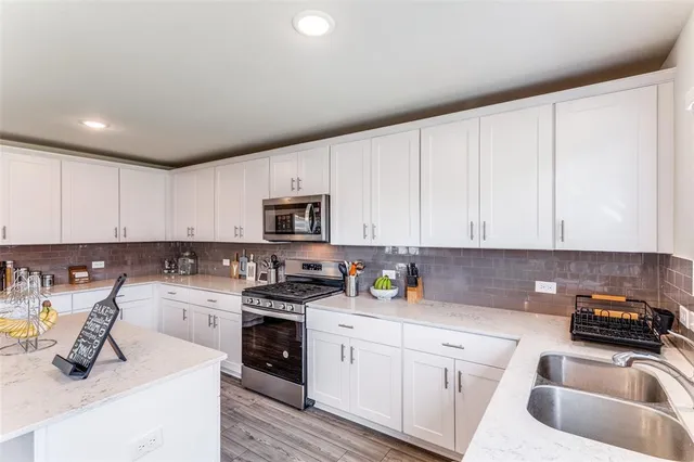 a kitchen with stainless steel appliances granite countertop white cabinets sink and stove