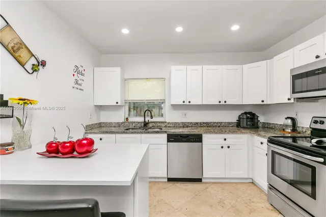 a kitchen with granite countertop a sink dishwasher white stove and cabinets
