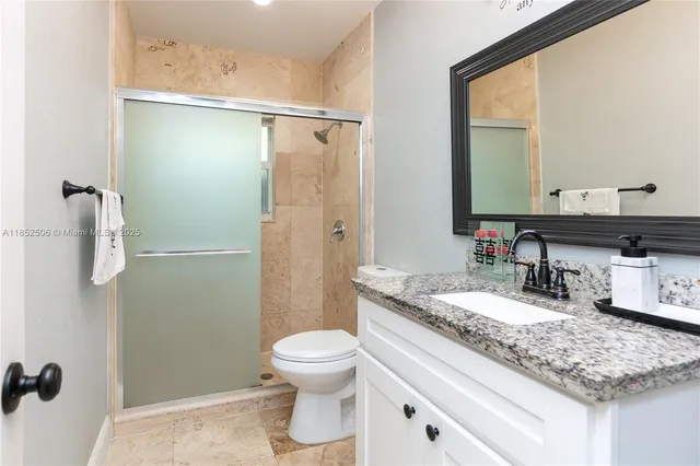 a bathroom with a granite countertop sink mirror vanity and toilet