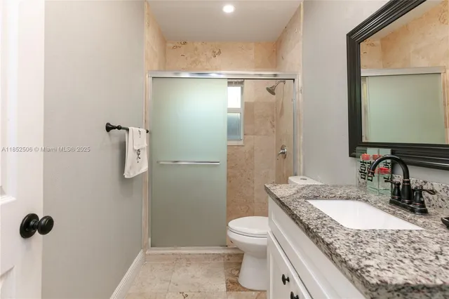 a bathroom with a granite countertop sink toilet and shower