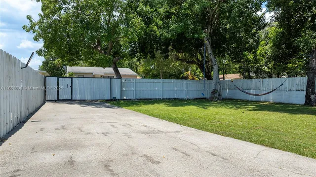a view of a backyard with large tree and wooden fence