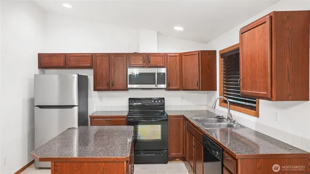 a kitchen with granite countertop a refrigerator stove and sink
