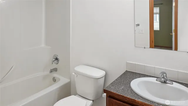 a bathroom with a granite countertop sink a toilet and bathtub