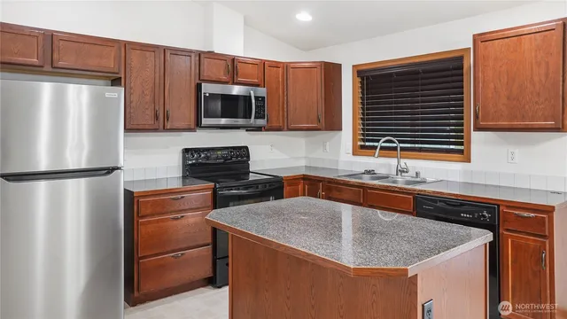 a kitchen with stainless steel appliances granite countertop a refrigerator a stove a sink a microwave and refrigerator